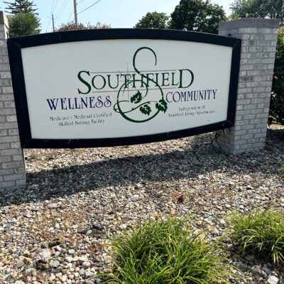 Sign for Southfield Wellness Community, with text indicating it is a Medicaid and medical center, skilled nursing facility, and independent and assisted living. The sign features a logo with a stylized tree and globe.