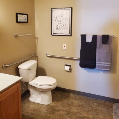 A bathroom with a white toilet, a framed sign that says 